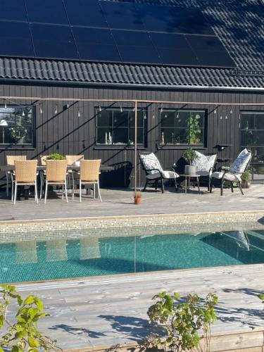 a pool with chairs and tables next to a building at Villa Golfgatan 32 Vintrosa Lanna in Vintrosa