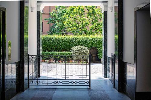 an open gate to a garden with a hedge at Solferino Suite in Milan