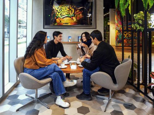 a group of people sitting around a table in a restaurant at ibis styles Lima San Isidro in Lima