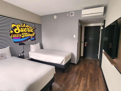 a room with two beds and a sign on the wall at ibis styles Lima San Isidro in Lima
