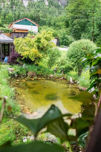 a pond in a garden with a house in the background at Landhaus HALLSTATT FEELING - Apartment - Self Check-in in Bad Goisern
