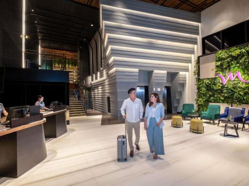 a man and a woman with a suitcase in a lobby at Mercure Tangerang Centre in Tangerang