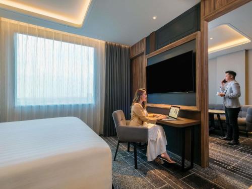a woman sitting at a desk in a hotel room at Mercure Tangerang Centre in Tangerang