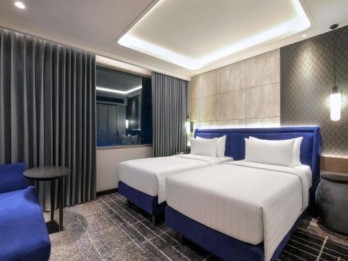 a hotel room with two beds and a table and chairs at Mercure Tangerang Centre in Tangerang