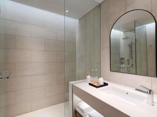 a bathroom with a tub and a sink and a mirror at Mercure Tangerang Centre in Tangerang