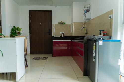 a kitchen with red cabinets and a refrigerator at Anandam Luxury Hill View 1BHK in Pune in Pune