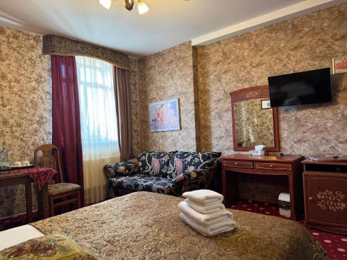 a hotel room with a bed and a couch and a television at Hotel Lavilia in Kyiv