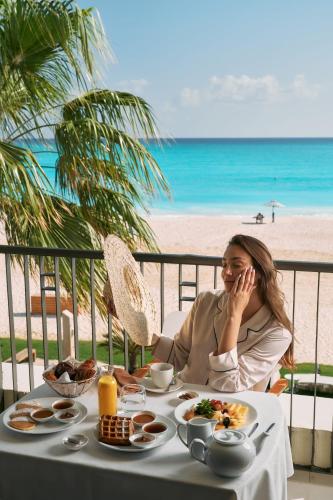 a woman sitting at a table with food on the beach at Al Alamein Hotel in El Alamein