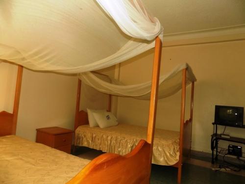 Postel nebo postele na pokoji v ubytování Palm Springs Hotel Masaka