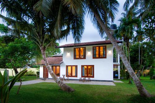 a white house with palm trees in front of it at Gedara Villa in Kalutara