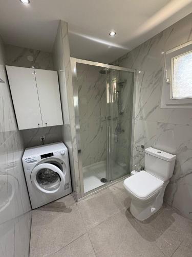 a bathroom with a washing machine and a toilet at Bungalow By Eftimiya in Nea Roda