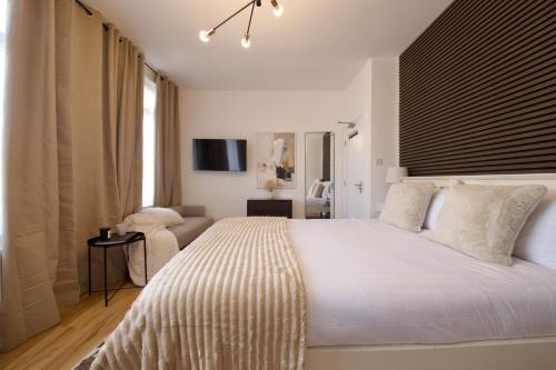 Un dormitorio con una gran cama blanca y un sofá. en NEST SUITE Studio Flat in North London, en Londres