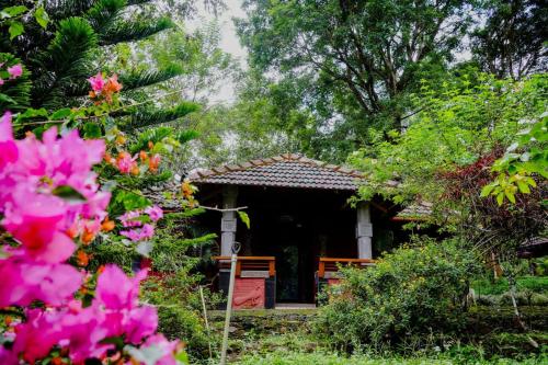 a small house with pink flowers in front of it at Misty Night Wayanad Bamboo Resort in Wayanad