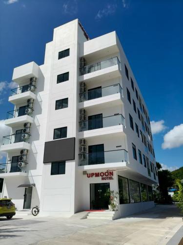 a white apartment building with a car parked in front at UPMOON Hotel in Ban Suan