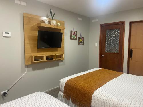 a bedroom with two beds and a flat screen tv at Cabañas Bosque Austral in Punta Arenas