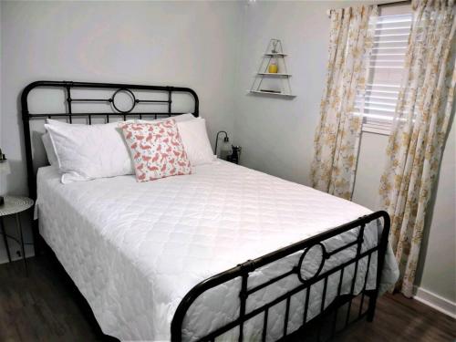 a bedroom with a bed with white sheets and a window at Best Location Quiet Cottage Pets Kitchen in Tallahassee