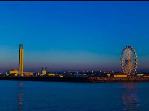 a ferris wheel in front of a city at dusk at Large Apartment, Sea View, Jacuzzi & Family Games in Fort de lʼEau