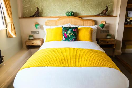 a bedroom with a large bed with yellow pillows at The White Hart Inn in Margaretting