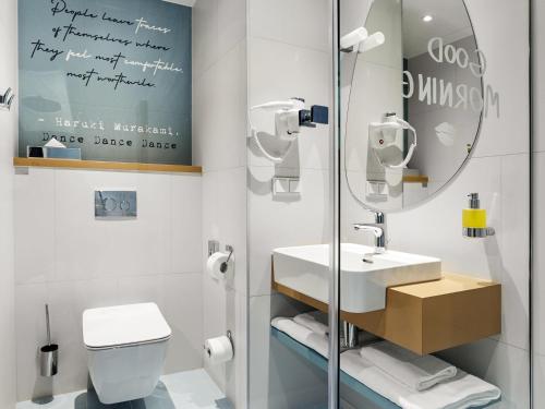 a bathroom with a sink and a mirror and a toilet at ibis Styles Kraków Centrum in Kraków