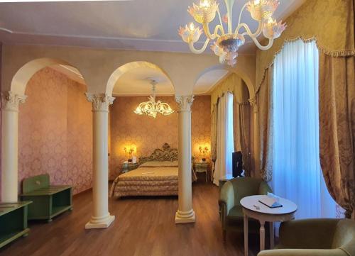 a bedroom with a bed with columns and a chandelier at Hotel Carlton On The Grand Canal in Venice