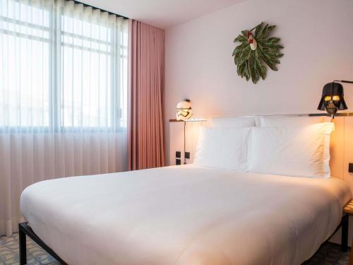 a bedroom with a large white bed and a window at Mama Shelter Lisboa in Lisbon