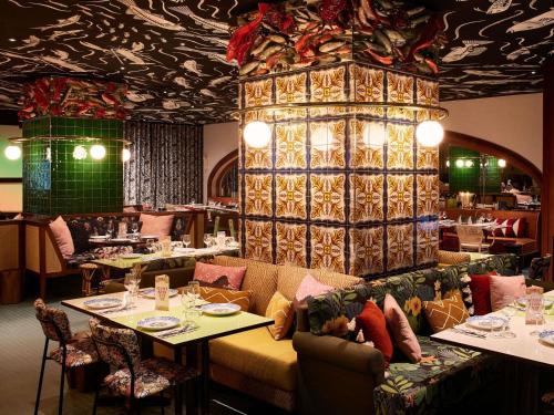 a restaurant with tables and a large chandelier at Mama Shelter Lisboa in Lisbon