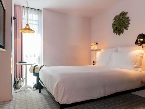 a bedroom with a large white bed and a window at Mama Shelter Lisboa in Lisbon