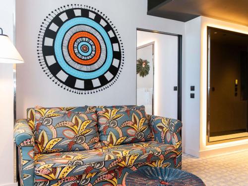 a living room with a couch and a clock on the wall at Mama Shelter Lisboa in Lisbon
