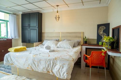 a bedroom with a large bed and a red chair at VillaromAfrica Staycations-Gold Suite in Eldoret