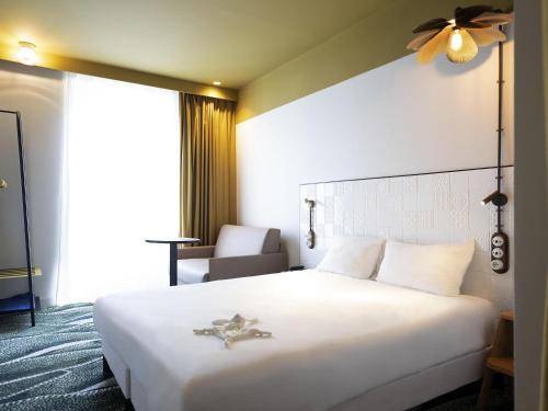 a bedroom with a large white bed with a ceiling fan at ibis Styles Paris Gare De Lyon TGV in Paris