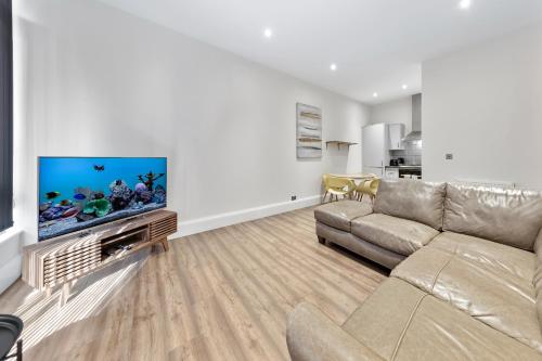 a living room with a couch and a flat screen tv at Shortlet Express, Stunning 3 bedroom Barking Apartment, by Train Station in Barking
