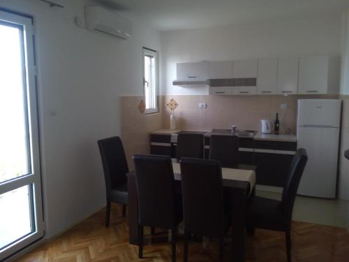 a kitchen with a table and chairs and a refrigerator at Sun Apartments in Tivat