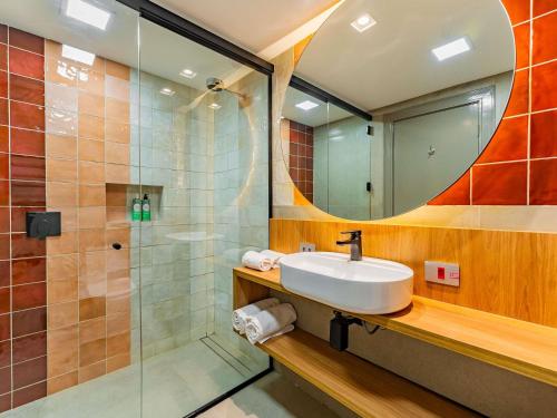 a bathroom with a sink and a shower with a mirror at Grand Mercure Curitiba Rayon in Curitiba