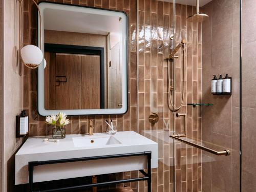 a bathroom with a sink and a shower with a mirror at Mercure Melbourne Doncaster in Doncaster