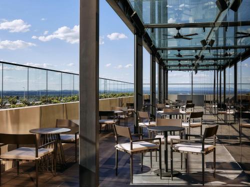 a restaurant with tables and chairs on a balcony at Mercure Melbourne Doncaster in Doncaster
