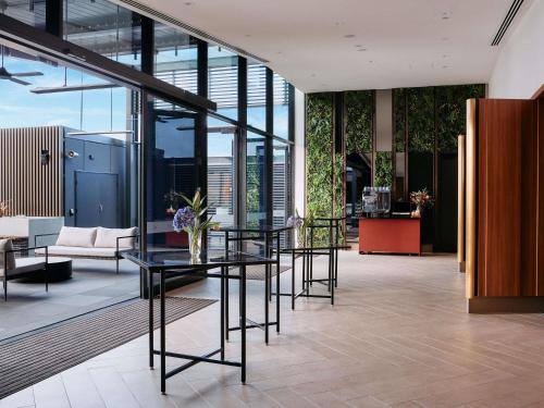 a lobby with a glass table and chairs at Mercure Melbourne Doncaster in Doncaster
