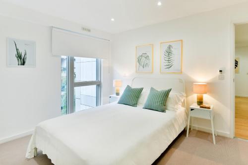 a white bedroom with a white bed and a window at Madison Hill - Clapham South 1 - Two bedroom flat in London