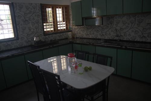 a white table in a kitchen with green cabinets at Aashiyana Idukki in Kūmudi