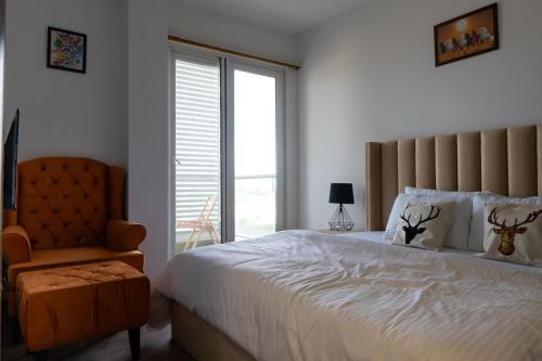 a bedroom with a bed and a chair and a window at Penta Square Executive Hotel Apartments City View DHA Lahore in Lahore