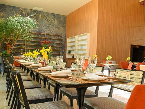 a dining room with a long table with chairs and wine glasses at Novotel Santa Cruz De La Sierra in Santa Cruz de la Sierra