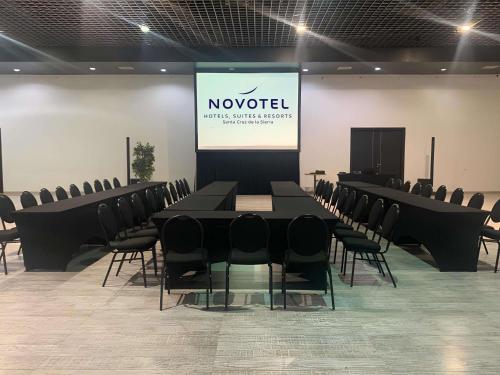 a conference room with a table and chairs and a screen at Novotel Santa Cruz De La Sierra in Santa Cruz de la Sierra