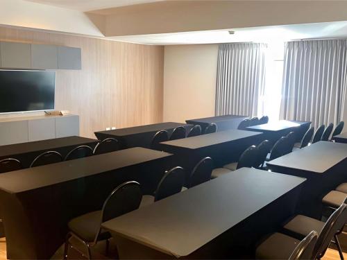 a conference room with tables and chairs and a flat screen tv at Novotel Santa Cruz De La Sierra in Santa Cruz de la Sierra