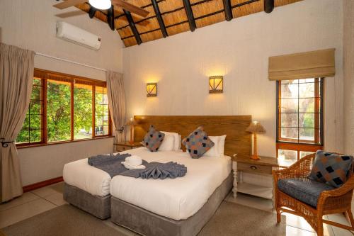 Kruger Park Lodge Unit No 304 في هازيفيو: غرفة نوم بها سرير كبير وكرسي