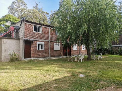 Una casa con sillas y un árbol en el patio. en Posada El Duende, en La Pedrera