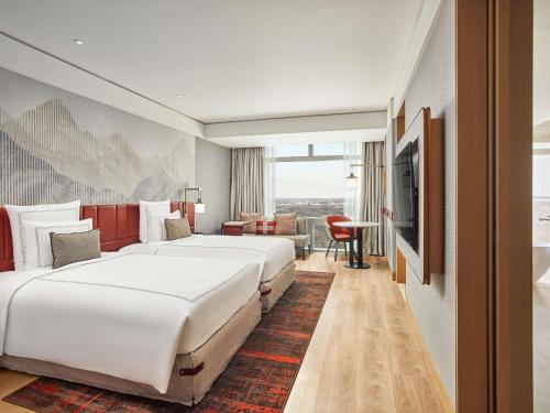 a hotel room with two beds and a television at Swissôtel Clark Philippines in Clark