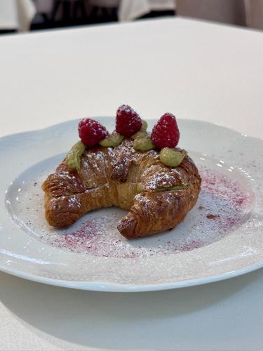 a pastry with raspberries on a plate on a table at Prestige Hotel in Stalowa Wola