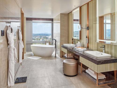 a bathroom with a large tub and a sink and a tub at Swissôtel Clark Philippines in Clark