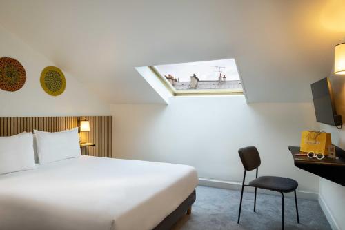 a hotel room with a bed and a skylight at Hôtel Korner Châtelet in Paris