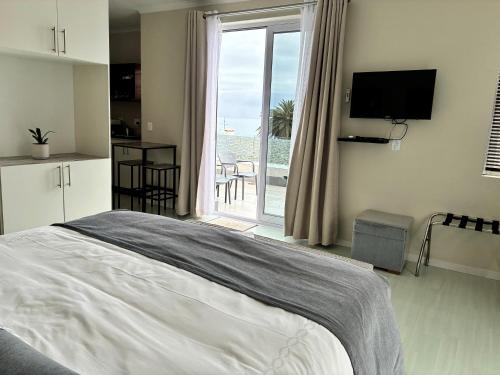 a bedroom with a bed and a view of a balcony at Manor on the Bay in Gordonʼs Bay