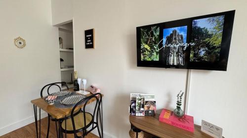 a room with a table and a television on the wall at La Bulle Millésimée - à deux pas de la Gare et de l'Avenue de Champagne in Épernay